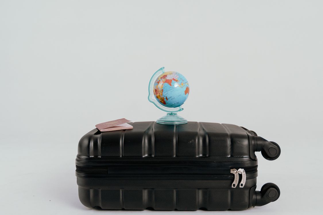 A small globe and a passport resting on a black suitcase, the set-up for a multi-country trip that suits a regional eSIM