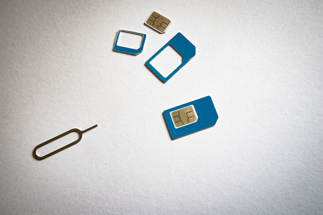 Two SIM cards and an ejector tool on a white surface, a reminder that eSIM plans replace this hardware