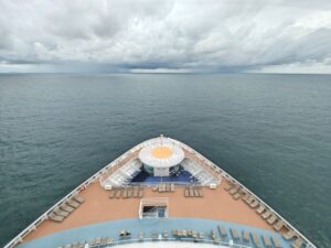 The bow of a cruise ship with deckchairs and open sea, where fly-cruise flight check-in ends