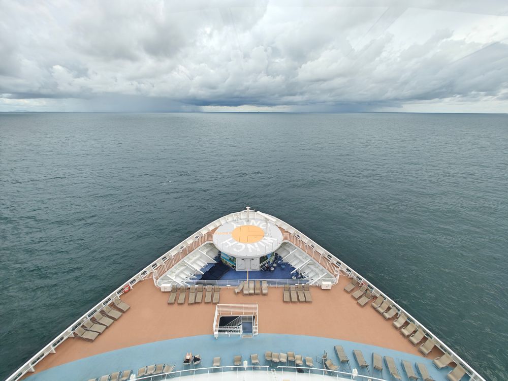 The bow of a cruise ship with deckchairs and open sea, where fly-cruise flight check-in ends