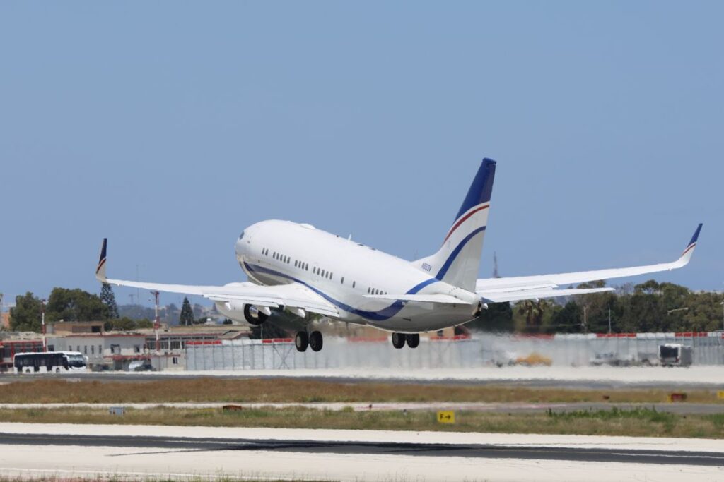 A white jet with blue and red tail stripes lifts off a runway on a clear day, as departures do from Gatwick Airport terminals