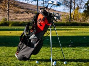 Jet2 sports equipment: a red and black golf bag standing on a practice green with clubs and balls