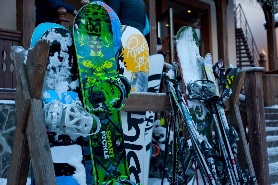 A row of colourful snowboards and skis propped on a wooden rack outside a ski lodge