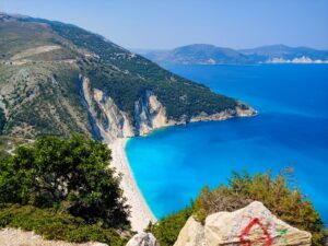 Is Kefalonia expensive: aerial view of Myrtos Beach with white cliffs, turquoise water and the Ionian coast beyond