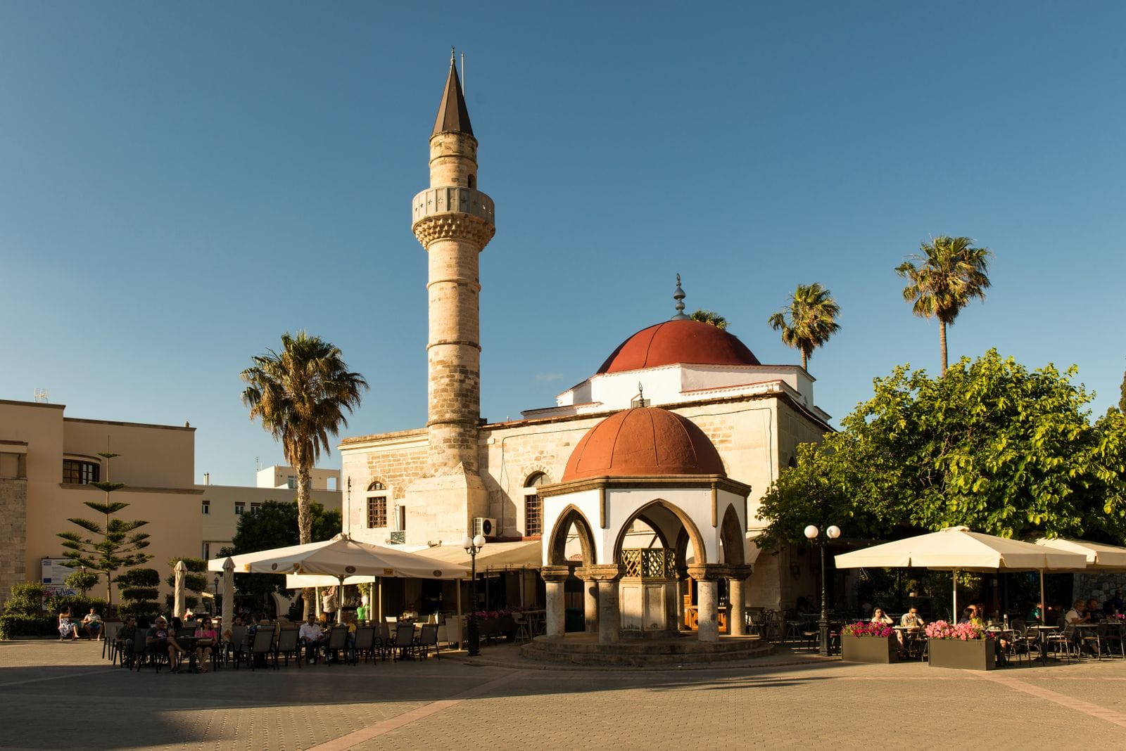 The Defterdar Mosque and its minaret beside the cafe-lined Eleftherias Square in Kos Town under a clear sky