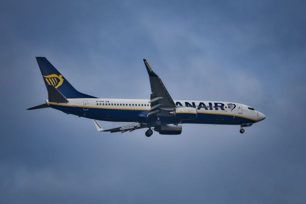 A Ryanair Boeing 737 in flight against a cloudy sky